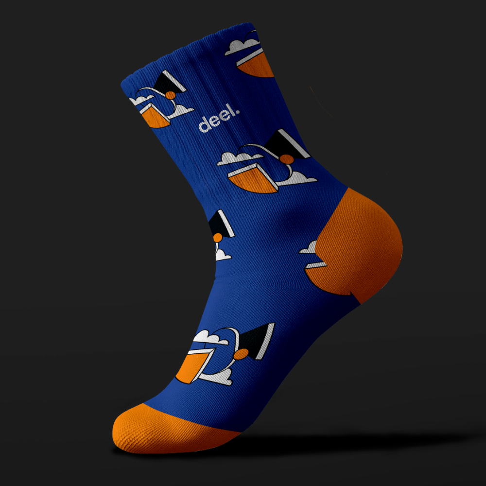Small Business 24 Blue sock with an orange heel and toe, featuring a cartoon graphic of a person with a hat and sunglasses against a dark background. The word deel. is printed near the top, showcasing unlimited graphic design creativity.