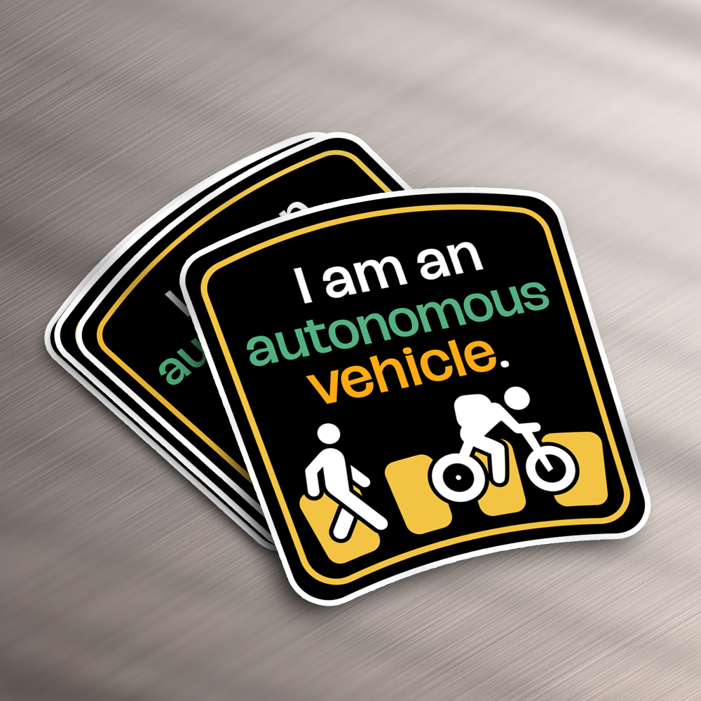 Small Business 16 These stickers, perfect for a design subscription, flaunt a traffic-themed motif with I am an autonomous vehicle in white, green, and orange. Below this text, icons depict a pedestrian, cyclist, and car against a black backdrop framed in white.