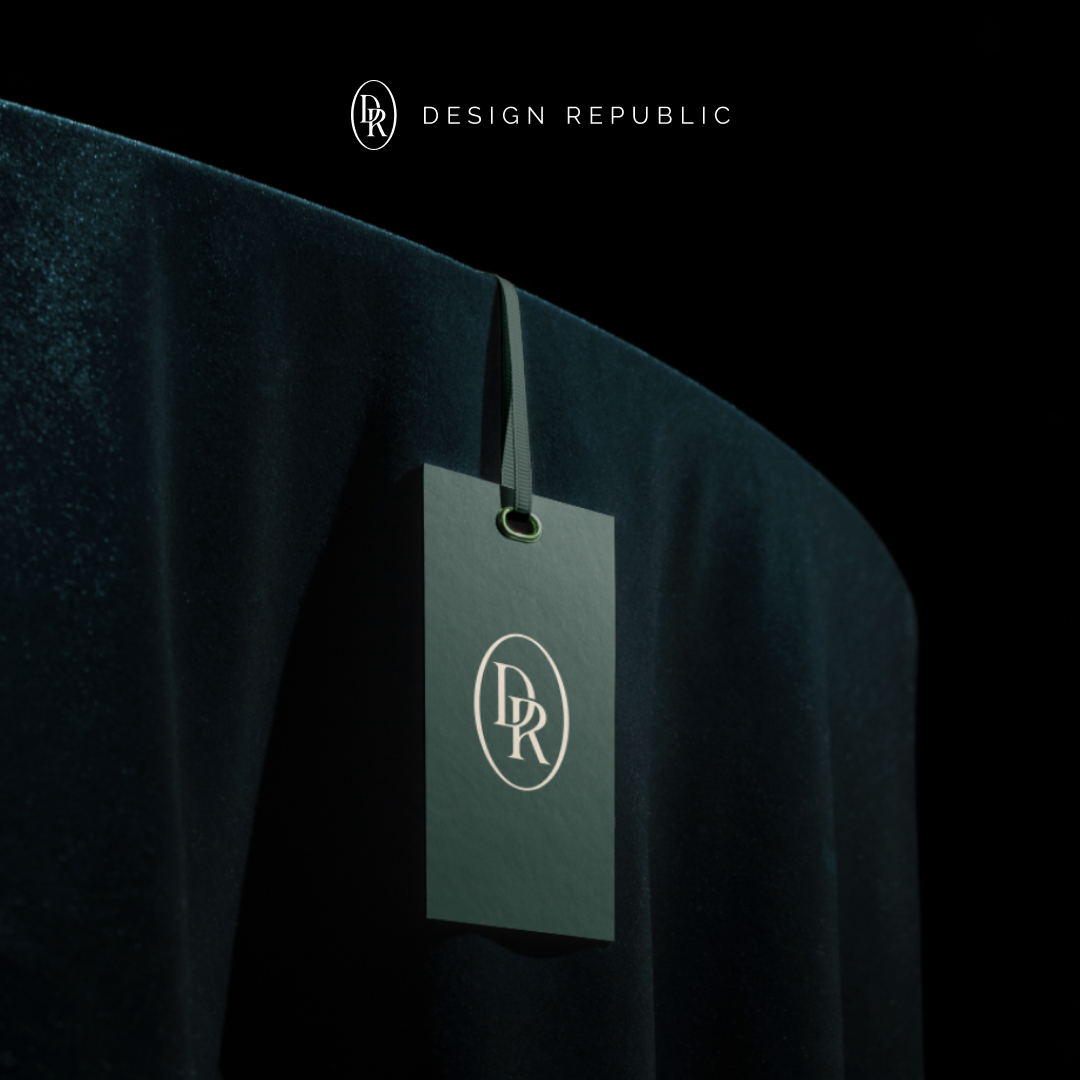 Small Business 8 A sleek black tag with the DR logo hangs on a luxurious dark green velvet fabric, symbolizing an exclusive design subscription. The text DESIGN REPUBLIC is elegantly displayed above in minimalist style, set against a dark background.